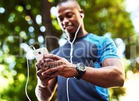 This is what I call connection on the go. a handsome young man listening to music and using his cellphone while exercising outdoors in the city.