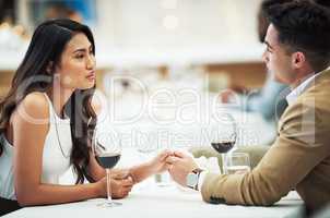 Romance is on the table tonight. an affectionate young couple holding hands while sitting at a table in a restaurant.