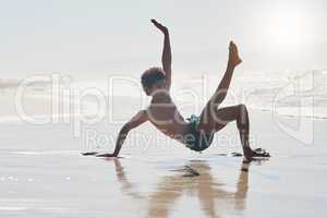 I am passionate about my dancing. Full length shot of a handsome young man performing a challenging dance sequence on the beach during the day.