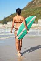 Im ready to get wet and wavy. a young woman out at the beach with her surfboard.