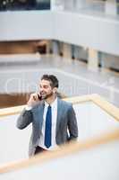 Securing success through his networks. a young businessman talking on a cellphone in an office.