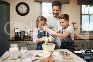 Im happy when my kids are happy. a man and his two children baking in the kitchen at home.