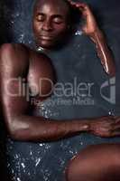 All muscle, all man. a handsome young man submerged in a bath filled with dark water.