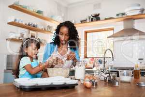 Baking is fun and oh so rewarding. a woman baking at home with her young daughter.