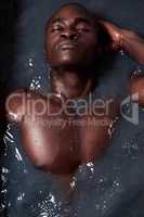 Take your stress to the tub. a handsome young man submerged in a bath filled with dark water.