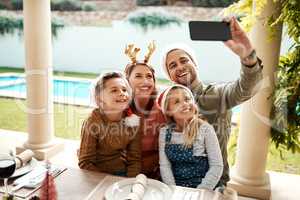 Merry Christmas, from my family to yours. a family of four taking a selfie together on Christmas day.