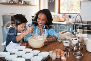 Whisk away little chef. a woman baking at home with her young son.