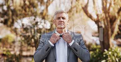 He knows the importance of a perfect necktie. Cropped portrait of a handsome mature bridegroom adjusting his necktie while preparing for his wedding outdoors.