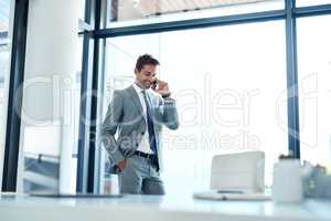 Yes, my business is doing well. a businessman talking on his cellphone while standing in his office.