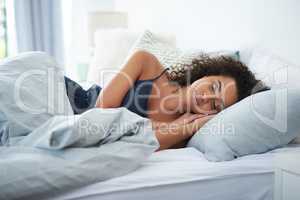 Just a few more hours of sleep. an attractive young woman sleeping under a duvet in bed during the morning.
