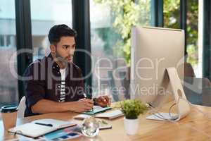 Working on my editing skills. a handsome young businessman sitting alone in his office and editing images.