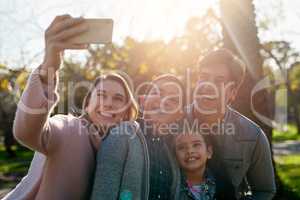 Our family moments become our greatest memories. a happy young family taking a selfie together in the park.
