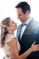 I could look into these eyes forever. a happy young couple standing indoors and holding each other affectionately after their wedding.