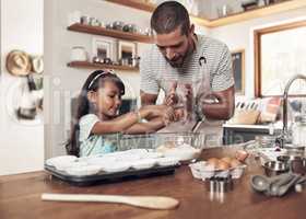 Happiness is having a large, loving, caring, close-knit family. a father teaching his daughter how to bake in the kitchen at home.