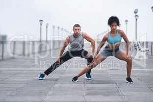 Stretch and hold. two sporty young people stretching while exercising outdoors.