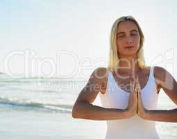 Choosing to take care of my body and my mind. an attractive young woman meditating early in the morning on the beach.