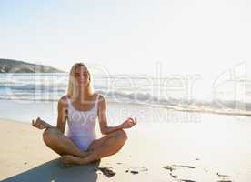 Focusing on my breath is best in the morning. Full length shot of an attractive young woman sitting with her legs crossed and meditating on the beach.