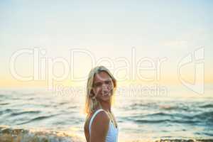 Days not at the beach are days wasted. Cropped portrait of an attractive young female smiling over her shoulder on the beach at sunset.