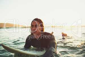 Ride with the tide. a young man paddling on a surfboard in the sea.