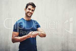 Always beating my best. Portrait of a sporty young man checking his watch while exercising outdoors.