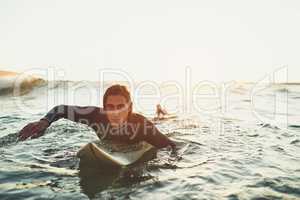 Youll often find me close to the waves. Portrait of a young man paddling on a surfboard in the sea.