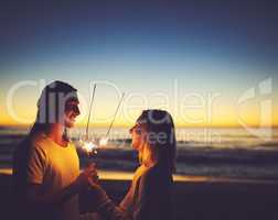 Within you is the light of a thousand suns. a young couple playing with sparklers on the beach at night.