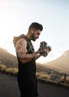 Bodies of steel are built with discipline. a sporty young man exercising with weights outdoors.