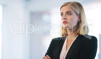 Big dreams and goals for the future. a confident young businesswoman standing with her arms folded inside of the office.