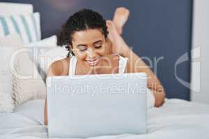 Got some interesting attention on her blog. an attractive young woman using her laptop while relaxing on her bed at home.