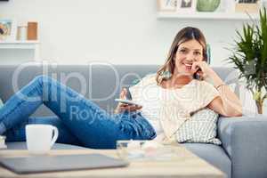 You can find entertainment at your fingertips. an attractive woman using her cellphone while relaxing at home.