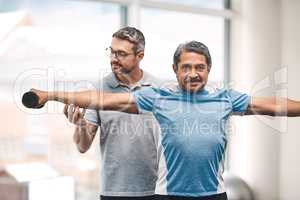 Exercise is vital in your senior years in life. a senior man exercising with dumbbells during a rehabilitation session with his physiotherapist.