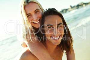 These sweethearts are totally in love. Portrait of a young man giving his girlfriend a piggyback ride at the beach.