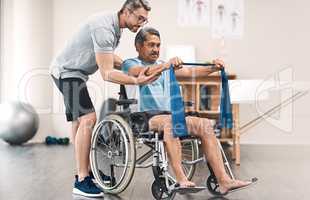 Strength lies in balance. Full length shot of a senior man in a wheelchair exercising with a resistance band along side his physiotherapist.