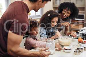 Spending the day baking as a family. a young couple baking at home with their two children.