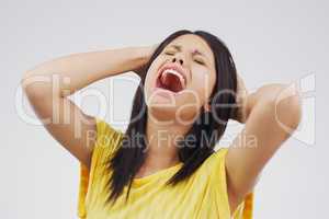 Oh the agony. Studio shot of a young woman crying while standing against a gray background.