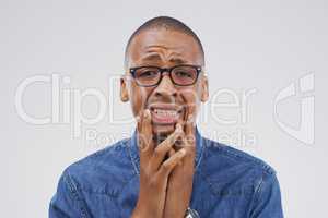 Why me. Studio shot of a young man crying while standing against a gray background.