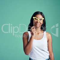 Putting her thinking glasses on. Studio shot of a beautiful young woman posing with prop glasses against a green background.