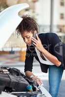 This is not something she can fix alone. an attractive young businesswoman calling roadside assistance after her car broke down.