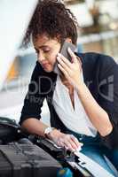 Looks like shes got a little waiting to do. an attractive young businesswoman calling roadside assistance after her car broke down.