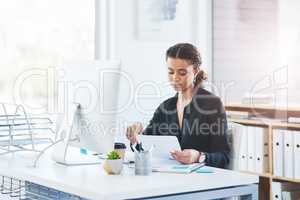 Its just another day to achieve a lot more success. a young businesswoman going through paperwork while working in an office.