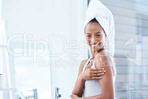 Take care of your body. a young woman applying moisturizer to her body.