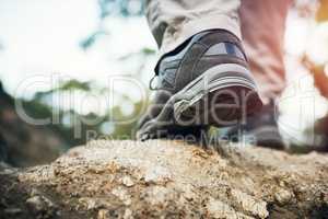 It just takes one step. Low angle shot of an unrecognizable man walking on rocks up a mountain outside during the day.