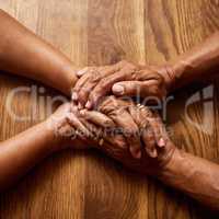 Together we handle anything thrown our way. High angle shot of an unrecognizable senior couple holding hands together over a wooden table at home.
