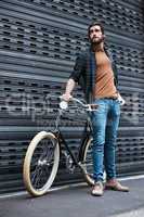 Modern day men roll around in these type of wheels. Full length shot of a handsome young man posing next to his bicycle outdoors.