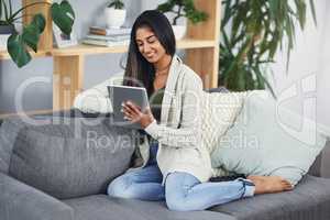 Find the best site to entertain your day off. a happy young woman using her digital tablet while relaxing on her couch at home.