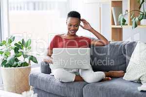 Loving this faster internet connection. a young woman relaxing on the sofa at home and using a laptop.