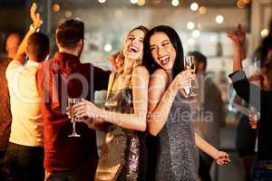 All eyes are on you. two cheerful young women having drinks while dancing on the dance floor of a club at night.