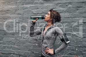 Staying hydrated during a workout. a young woman taking a water break while exercising outside.