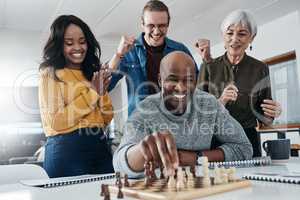 Theres a reason why hes our champion, he always wins. a mature businessman playing chess in his office with his colleagues rooting and watching in the background.