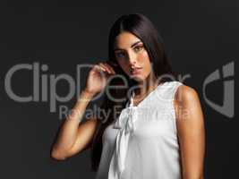 Elegance is when the inner beauty matches the outer. Portrait of an attractive young woman wearing a white blouse and posing alone against a dark background in the studio.